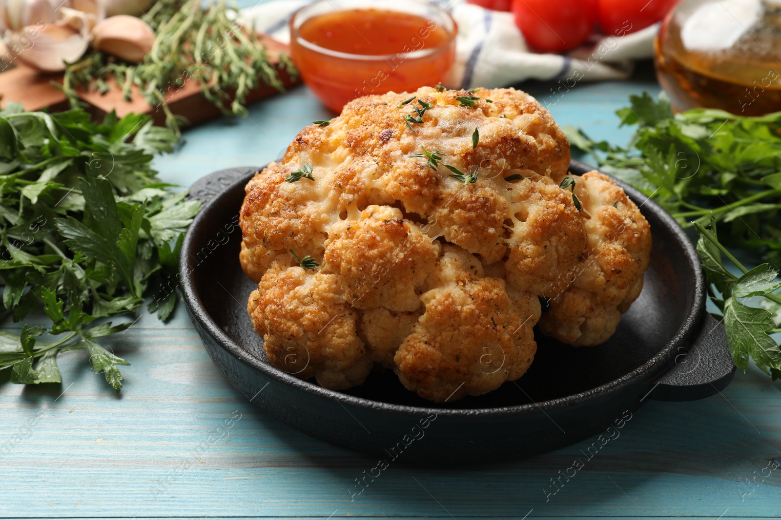 Photo of Delicious baked cauliflower in baking dish on light blue wooden table, closeup