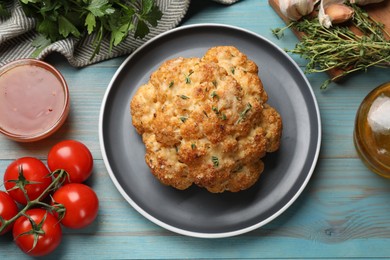 Photo of Delicious baked cauliflower and products on light blue wooden table, flat lay