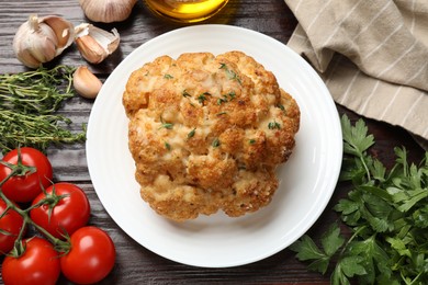 Delicious baked cauliflower, tomatoes and spices on wooden table, flat lay