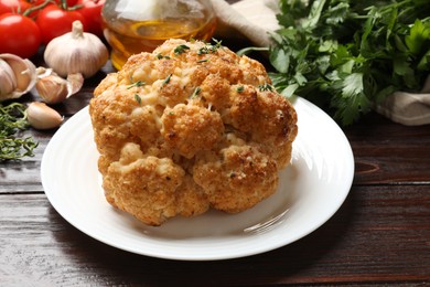 Delicious baked cauliflower and products on wooden table, closeup