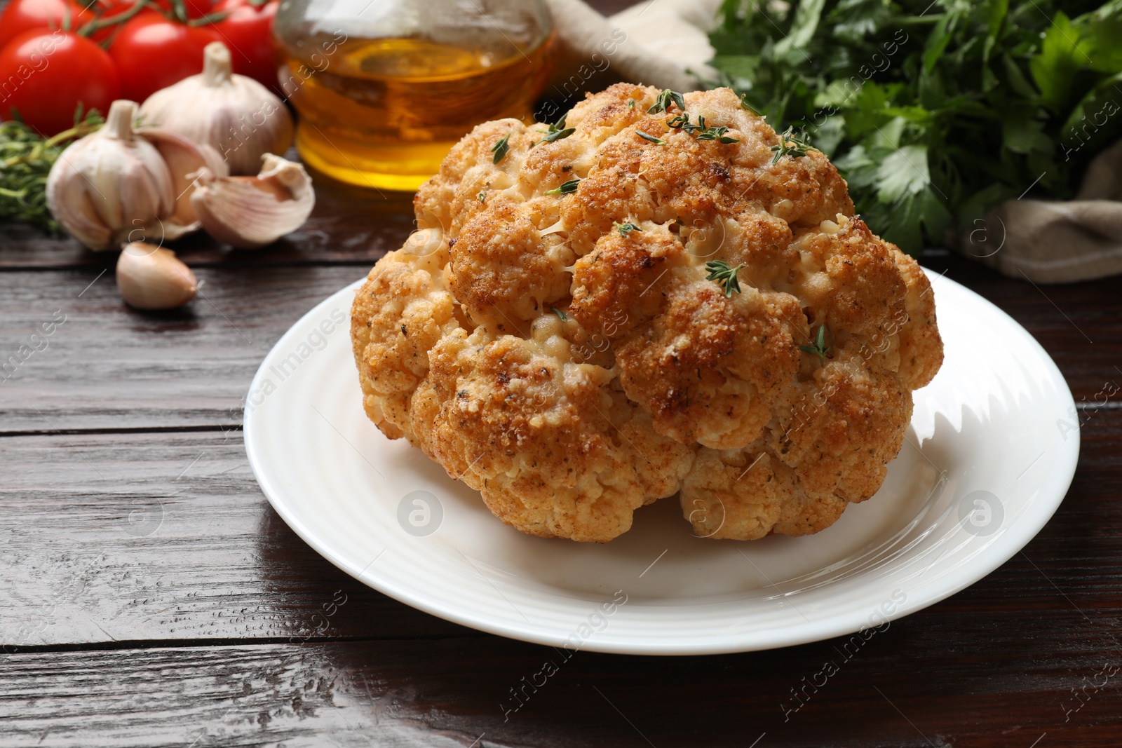 Photo of Delicious baked cauliflower and products on wooden table, closeup