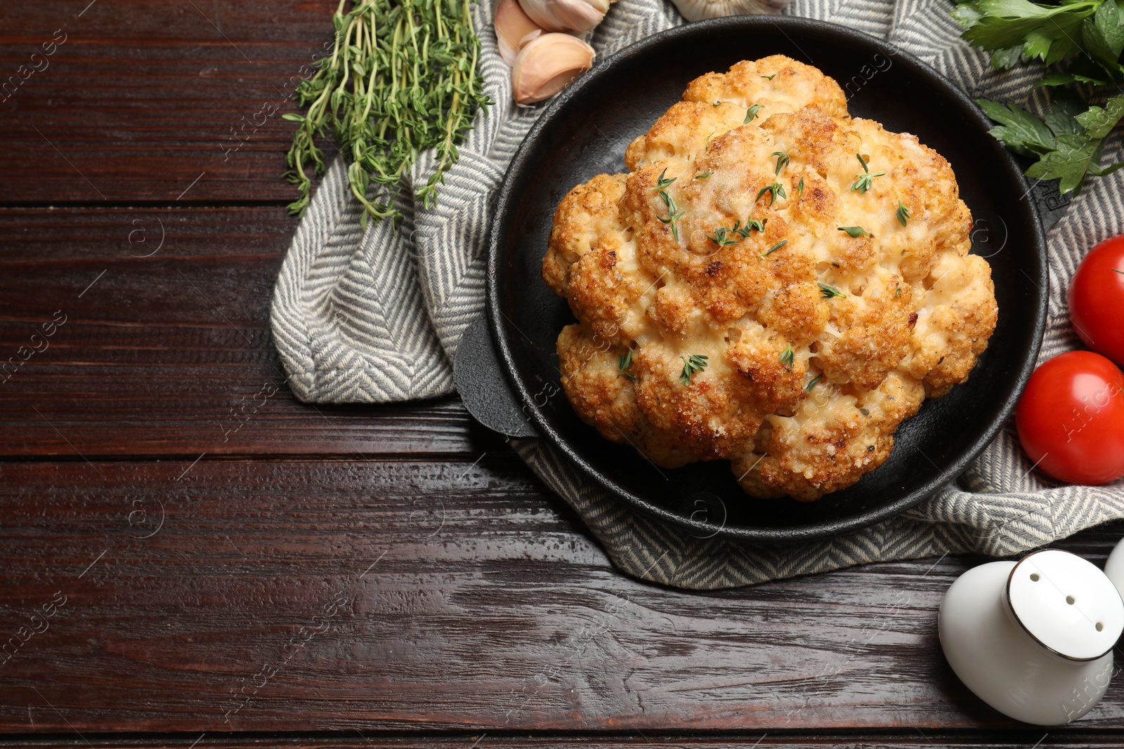 Photo of Delicious baked cauliflower in baking dish, tomatoes and spices on wooden table, flat lay. Space for text