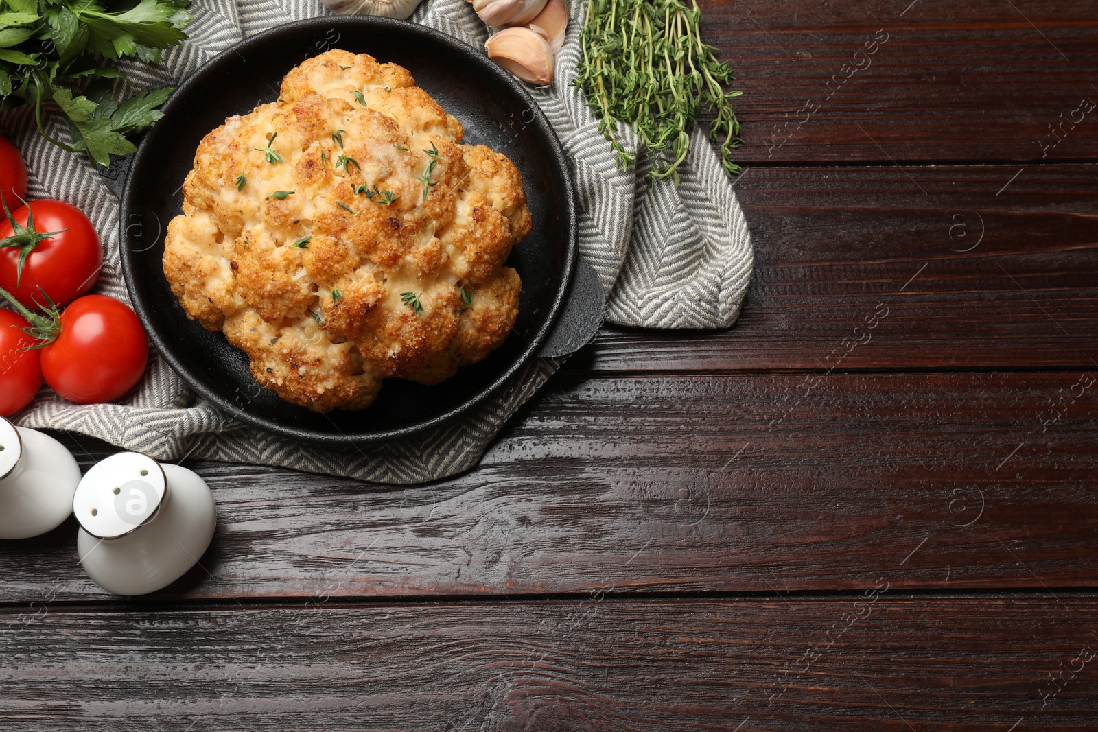 Photo of Delicious baked cauliflower in baking dish, tomatoes and spices on wooden table, flat lay. Space for text