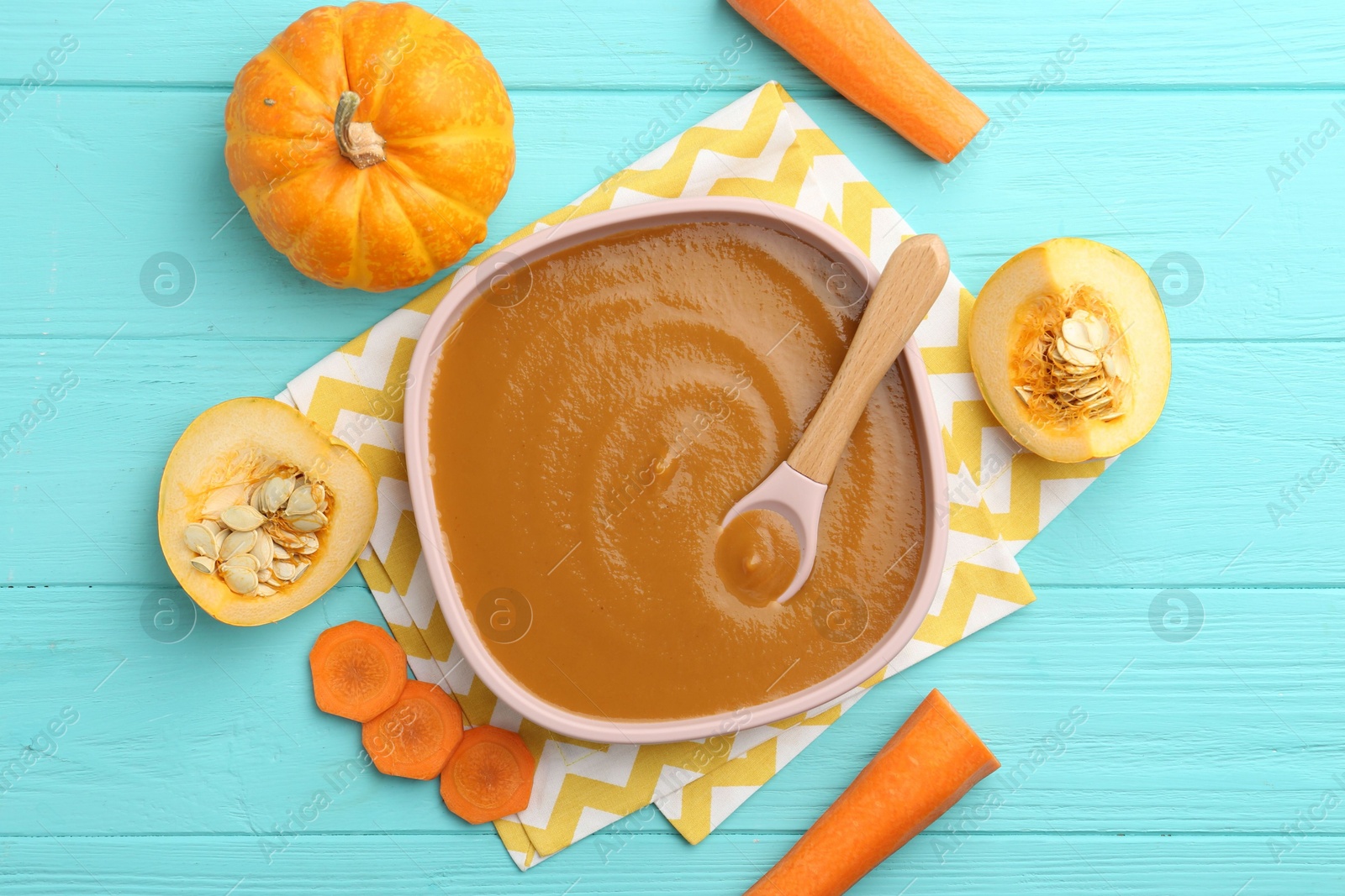 Photo of Delicious baby food in bowl and ingredients on light blue wooden table, flat lay