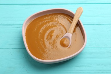 Photo of Delicious baby food in bowl on light blue wooden table