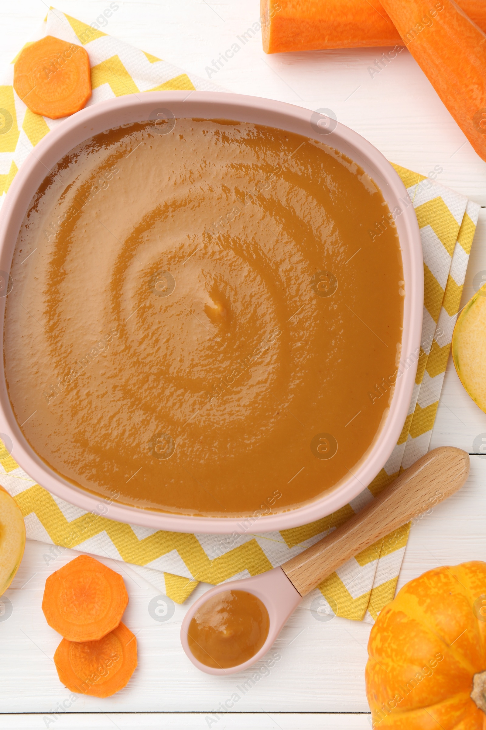 Photo of Delicious baby food in bowl and ingredients on white wooden table, flat lay