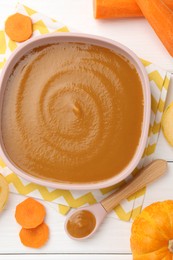 Photo of Delicious baby food in bowl and ingredients on white wooden table, flat lay