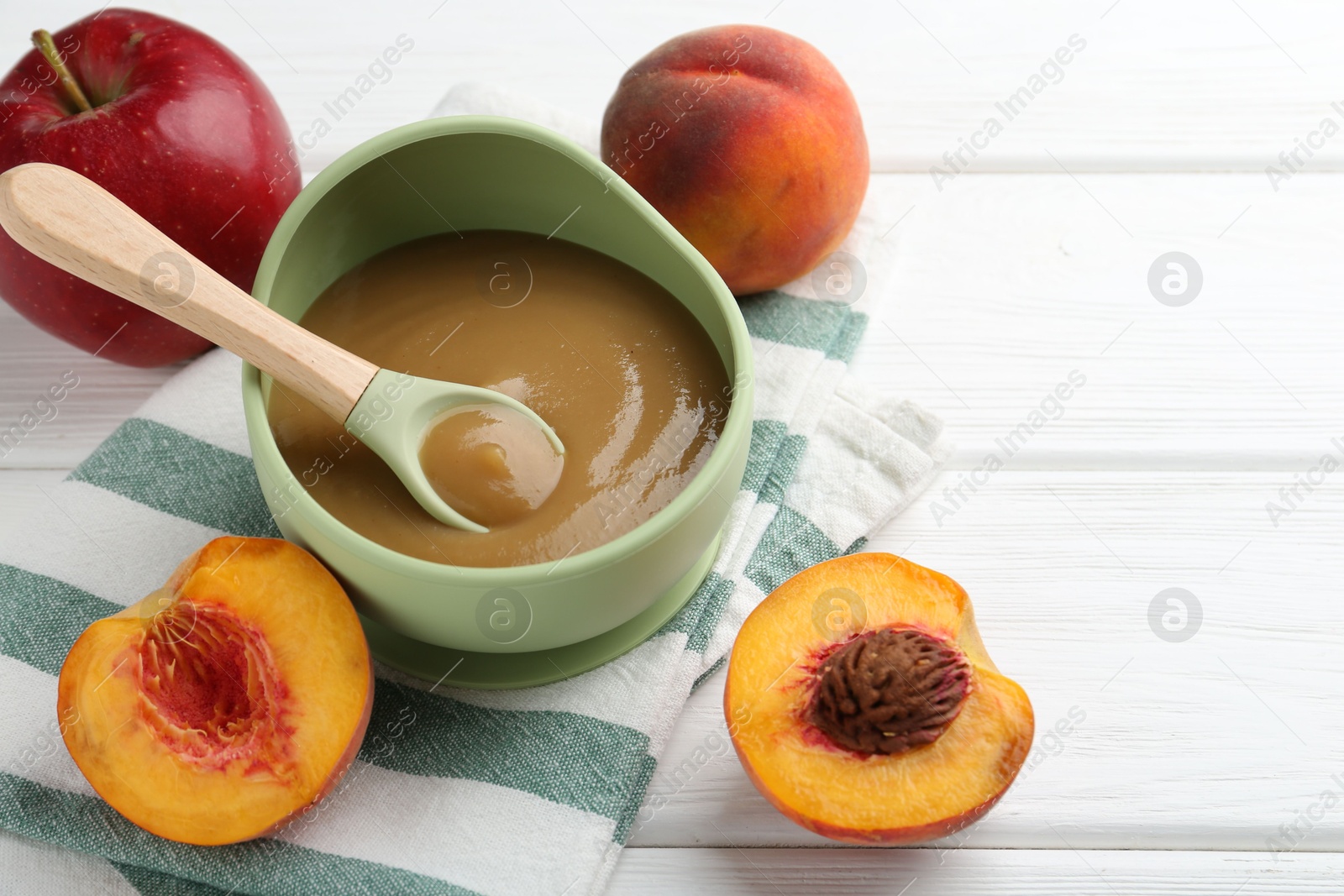 Photo of Delicious baby food in bowl and ingredients on white wooden table, closeup