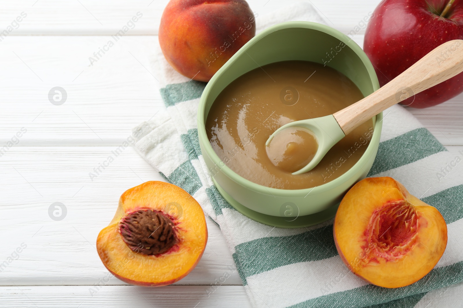 Photo of Delicious baby food in bowl and ingredients on white wooden table, closeup