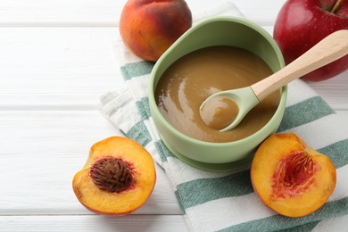 Photo of Delicious baby food in bowl and ingredients on white wooden table, closeup