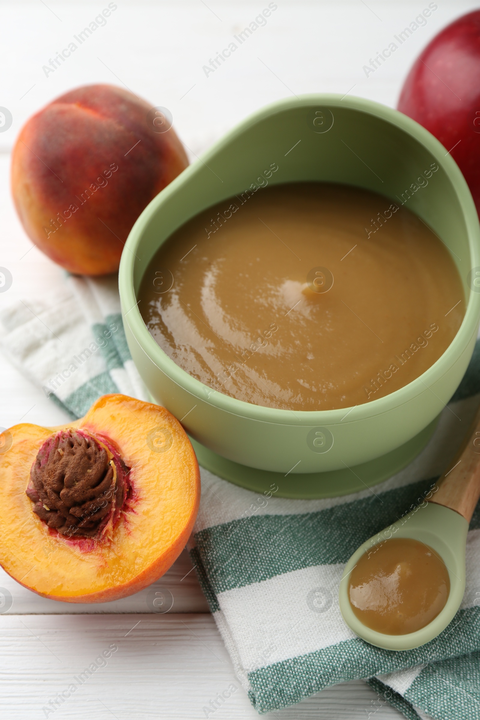 Photo of Delicious baby food in bowl and ingredients on white wooden table, closeup