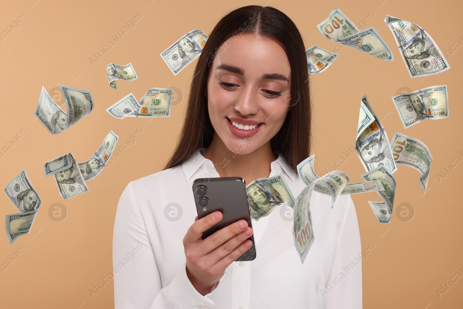 Image of Happy woman using mobile phone on dark beige background. Money out of device flying around her