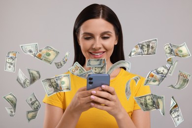 Image of Happy woman using mobile phone on grey background. Money flying out of device