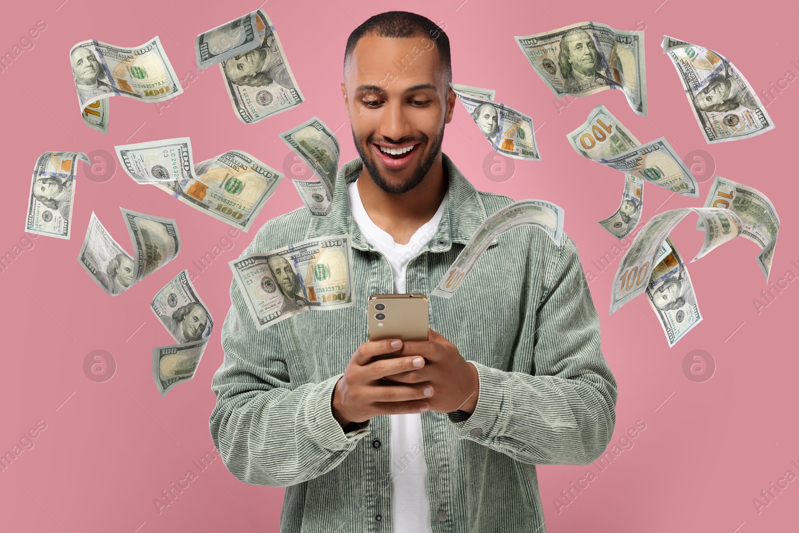 Image of Happy man using mobile phone on pink background. Money flying out of device