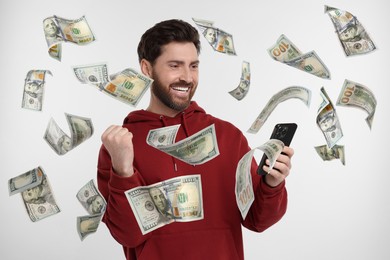 Image of Happy man using mobile phone on white background. Money flying out of device