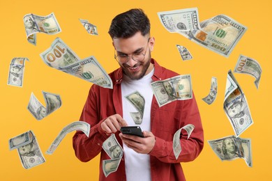 Happy man using mobile phone under money rain on violet background