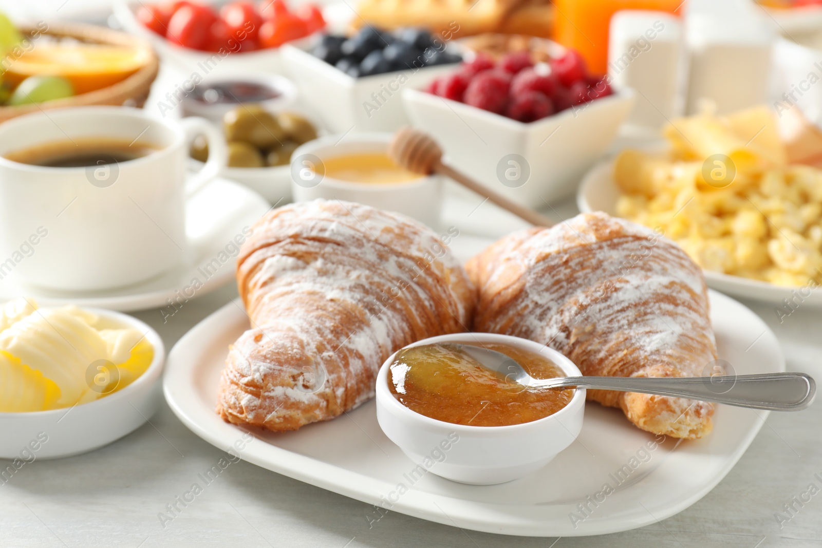 Photo of Tasty breakfast. Croissants, jam and other food on light table, closeup