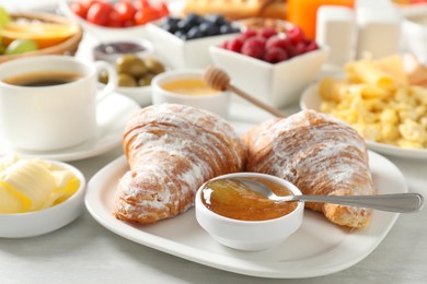 Tasty breakfast. Croissants, jam and other food on light table, closeup