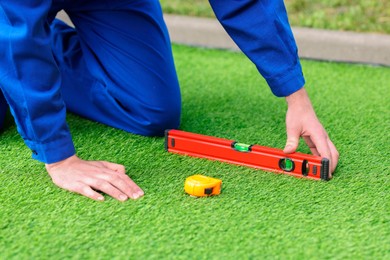 Man in uniform installing artificial turf outdoors, closeup