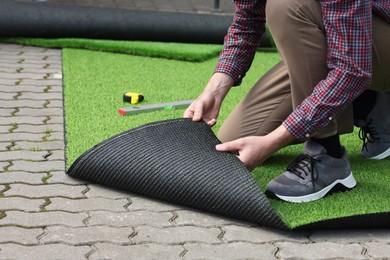 Man installing artificial turf outdoors, closeup view