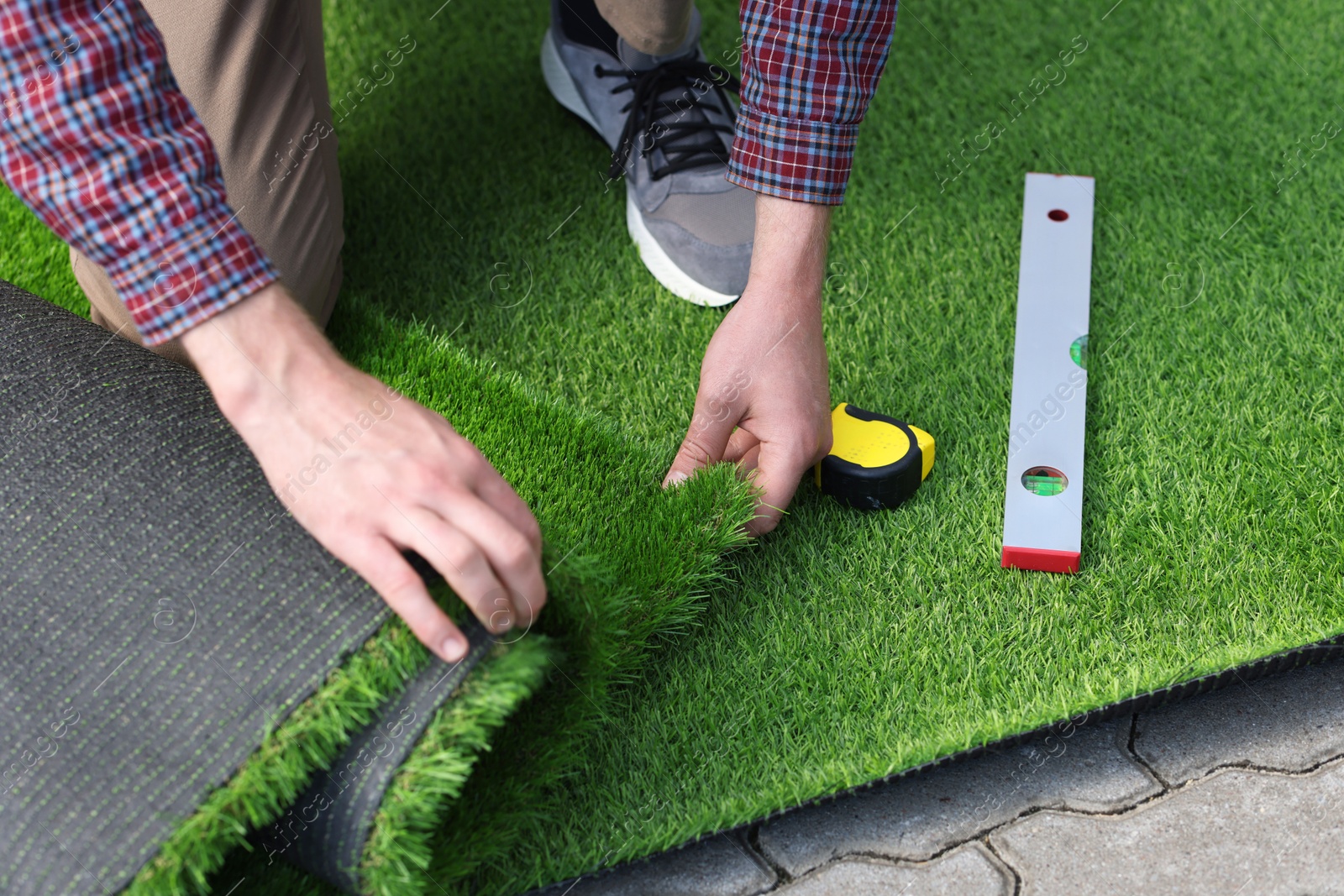 Photo of Man installing artificial turf outdoors, closeup view