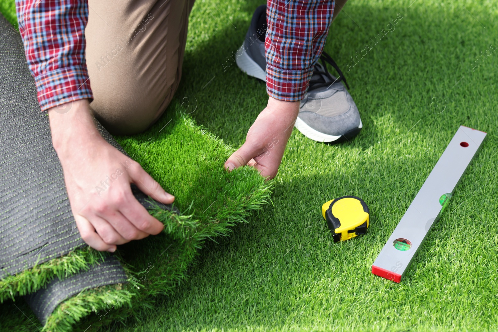 Photo of Young man installing artificial turf, closeup view