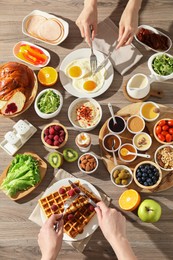 Photo of People having breakfast at wooden table, top view