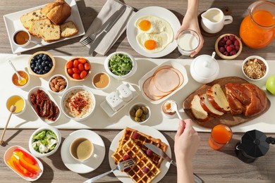 Photo of People having breakfast at wooden table, top view