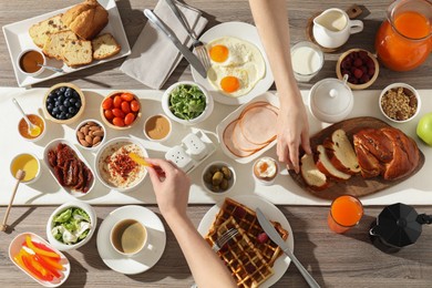 People having breakfast at wooden table, top view