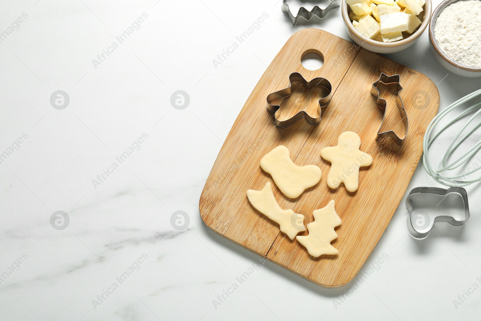 Photo of Raw cookies, cutters and ingredients on white marble table, flat lay. Space for text