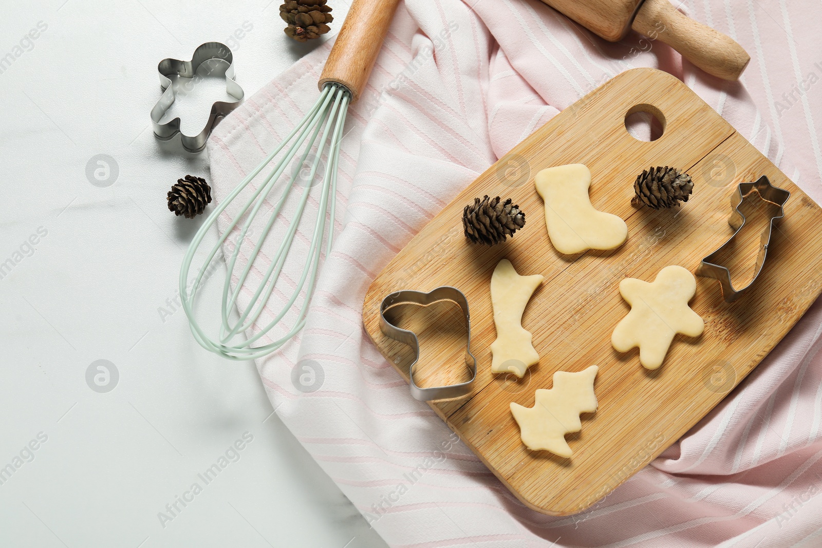 Photo of Raw cookies, cutters and whisk on white marble table, flat lay