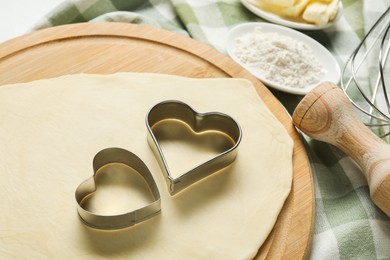 Raw dough and cookie cutters on table, closeup