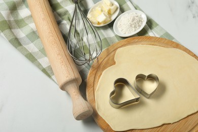 Photo of Raw dough, cookie cutters, flour, butter, whisk and rolling pin on white table, above view