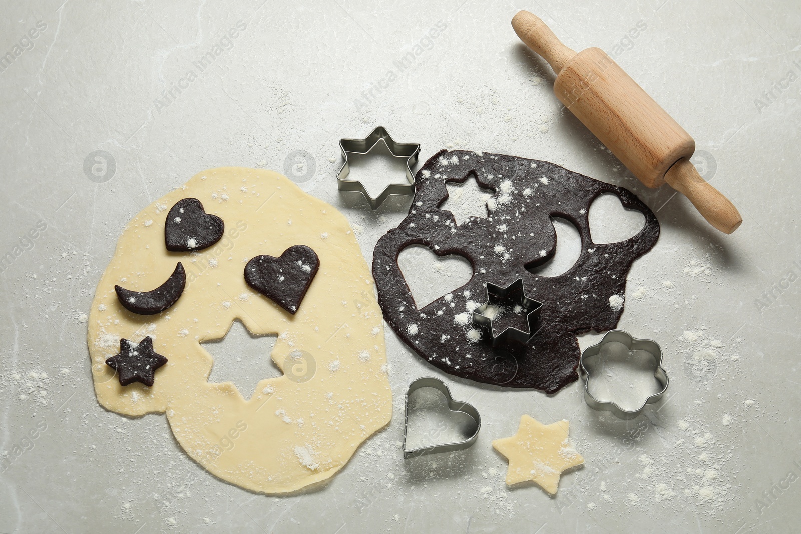 Photo of Raw doughs, rolling pin and cookie cutters on light table, flat lay