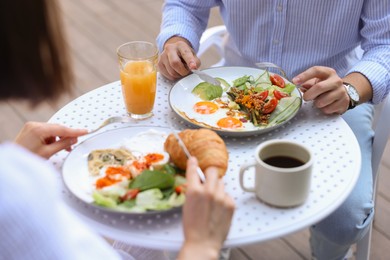 Photo of Couple having tasty breakfast in outdoor cafe, closeup