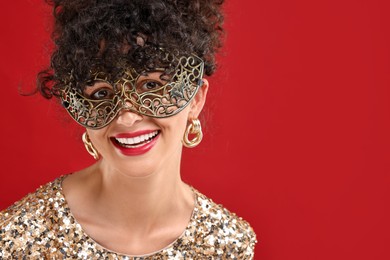 Photo of Smiling young woman wearing carnival mask on red background, space for text