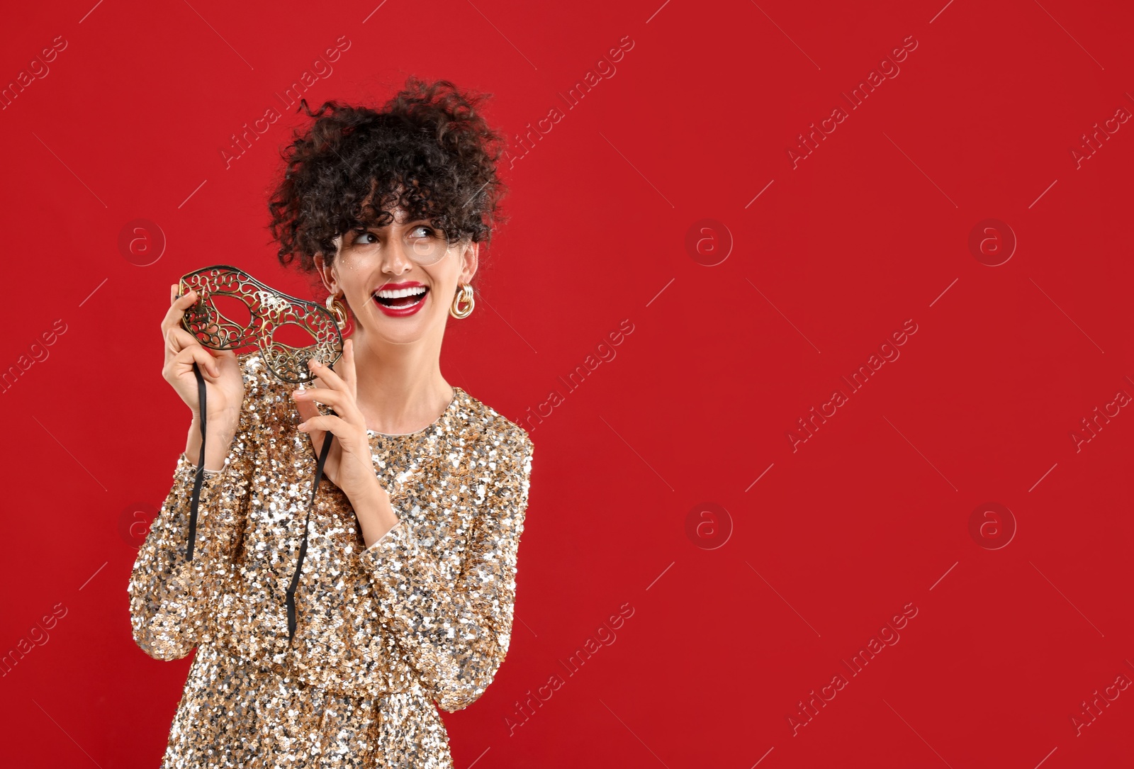 Photo of Smiling young woman with carnival mask on red background, space for text