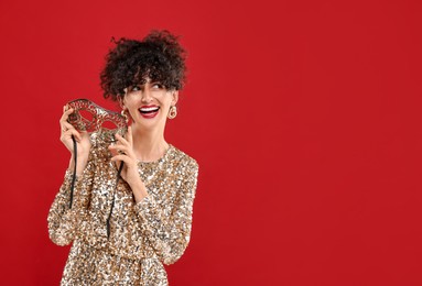 Photo of Smiling young woman with carnival mask on red background, space for text