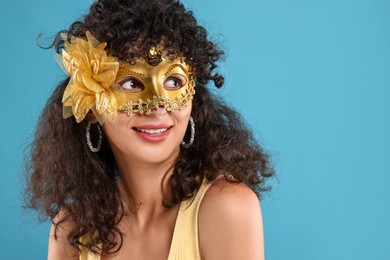 Photo of Happy young woman wearing carnival mask on light blue background