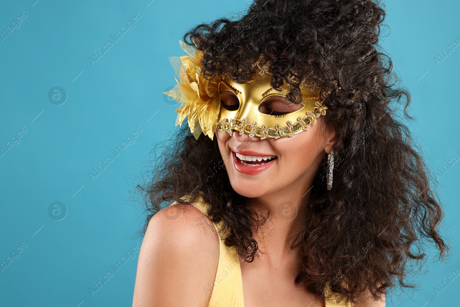 Photo of Happy young woman wearing carnival mask on light blue background