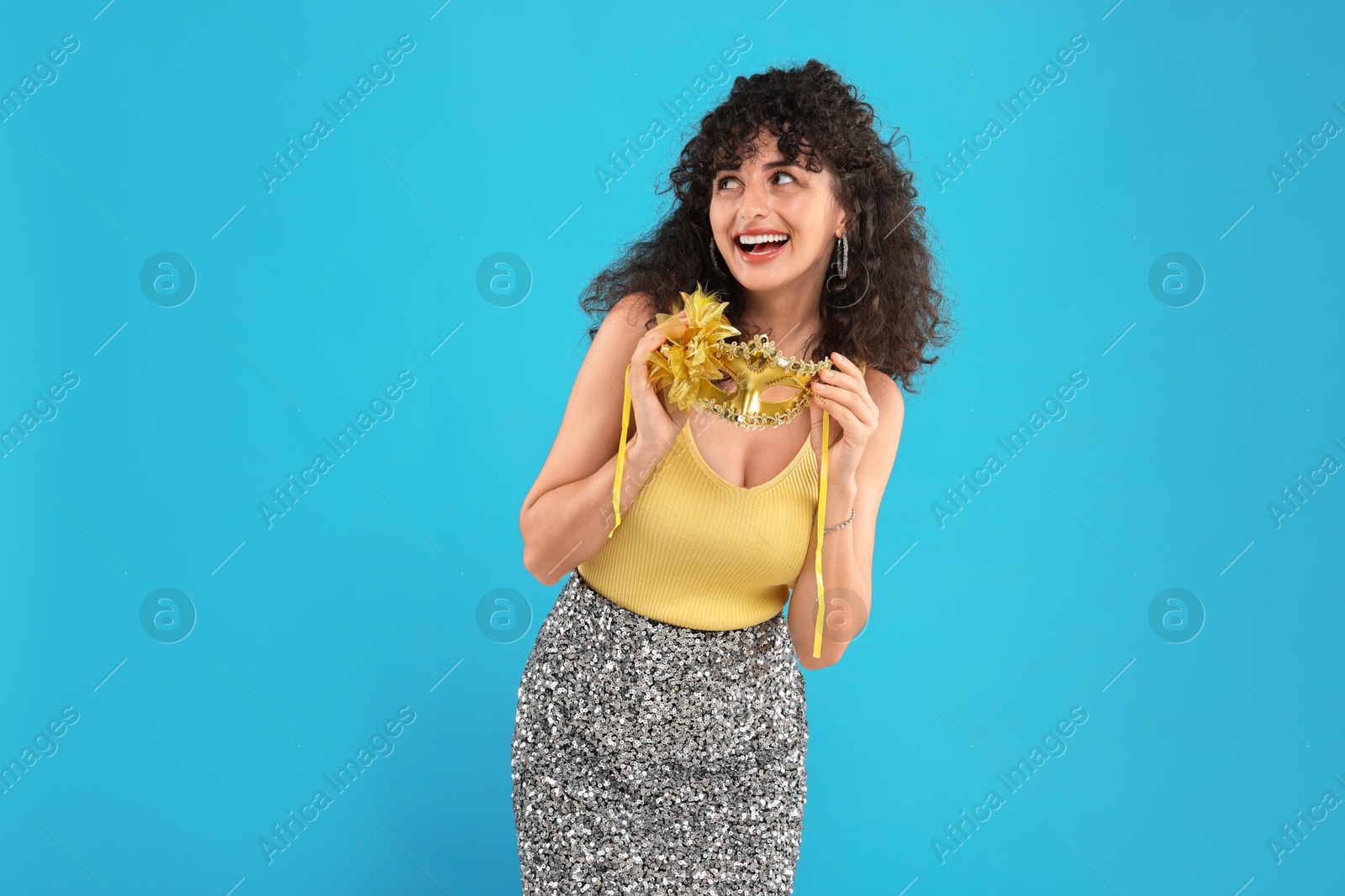 Photo of Happy young woman with carnival mask on light blue background