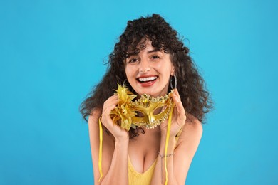 Photo of Happy young woman with carnival mask on light blue background