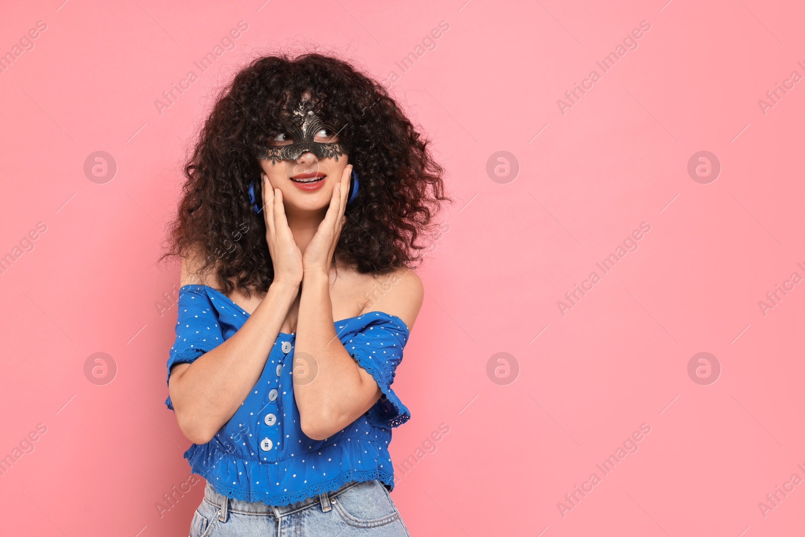 Photo of Beautiful young woman wearing carnival mask on pink background, space for text