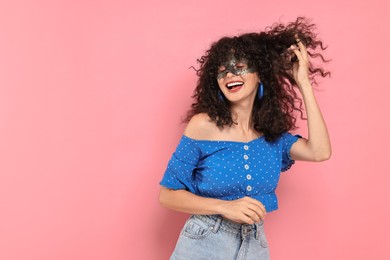 Happy young woman wearing carnival mask on pink background, space for text