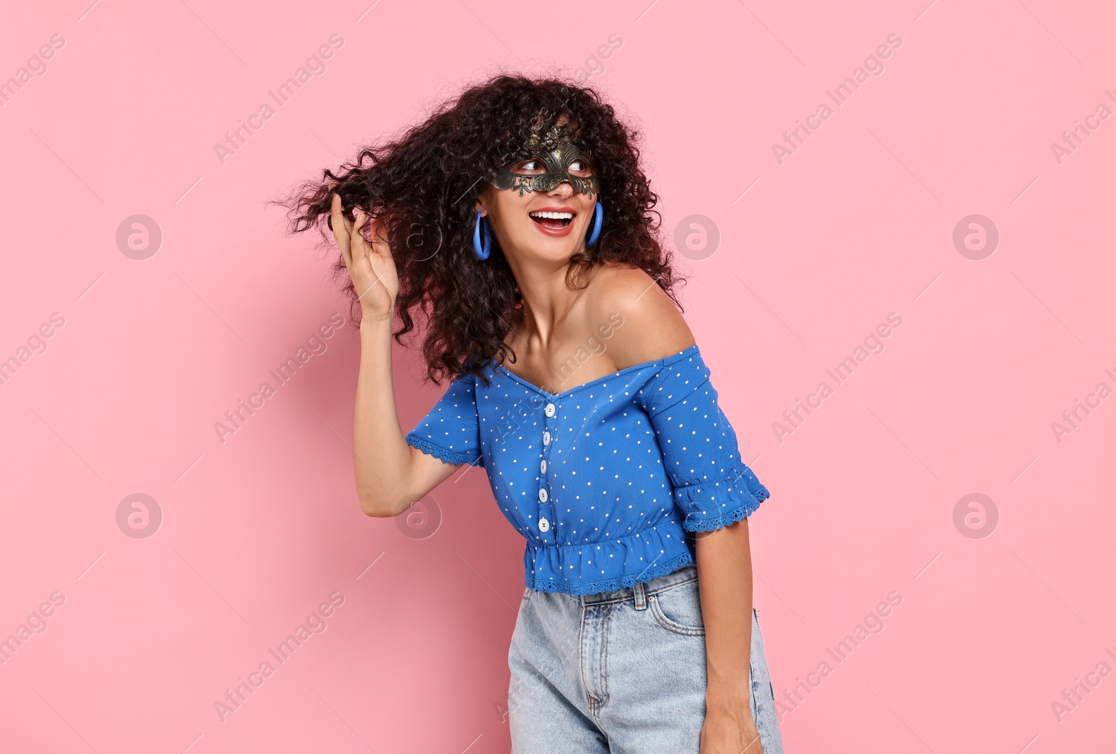 Photo of Happy young woman wearing carnival mask on pink background