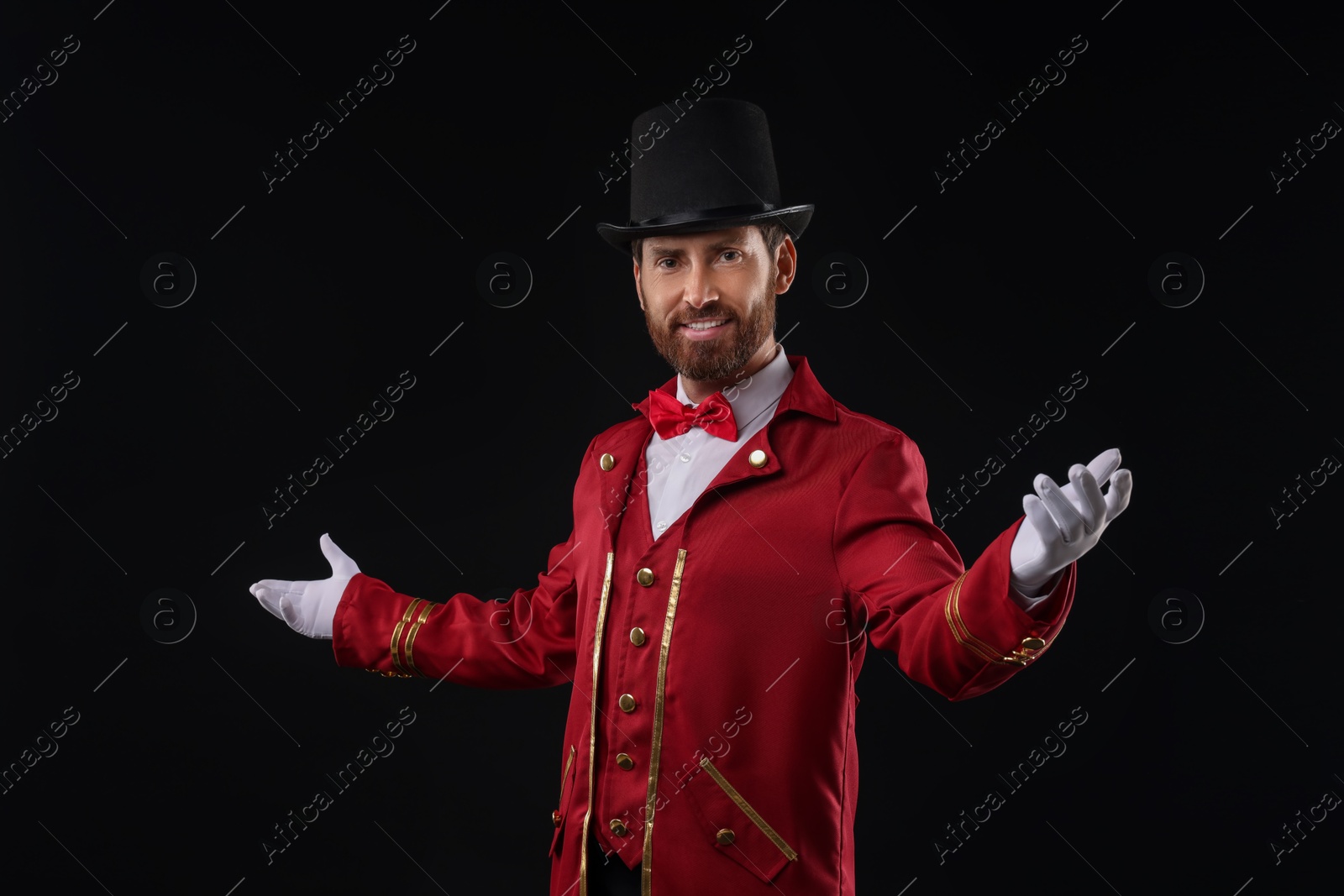 Photo of Portrait of showman in red costume and hat on black background