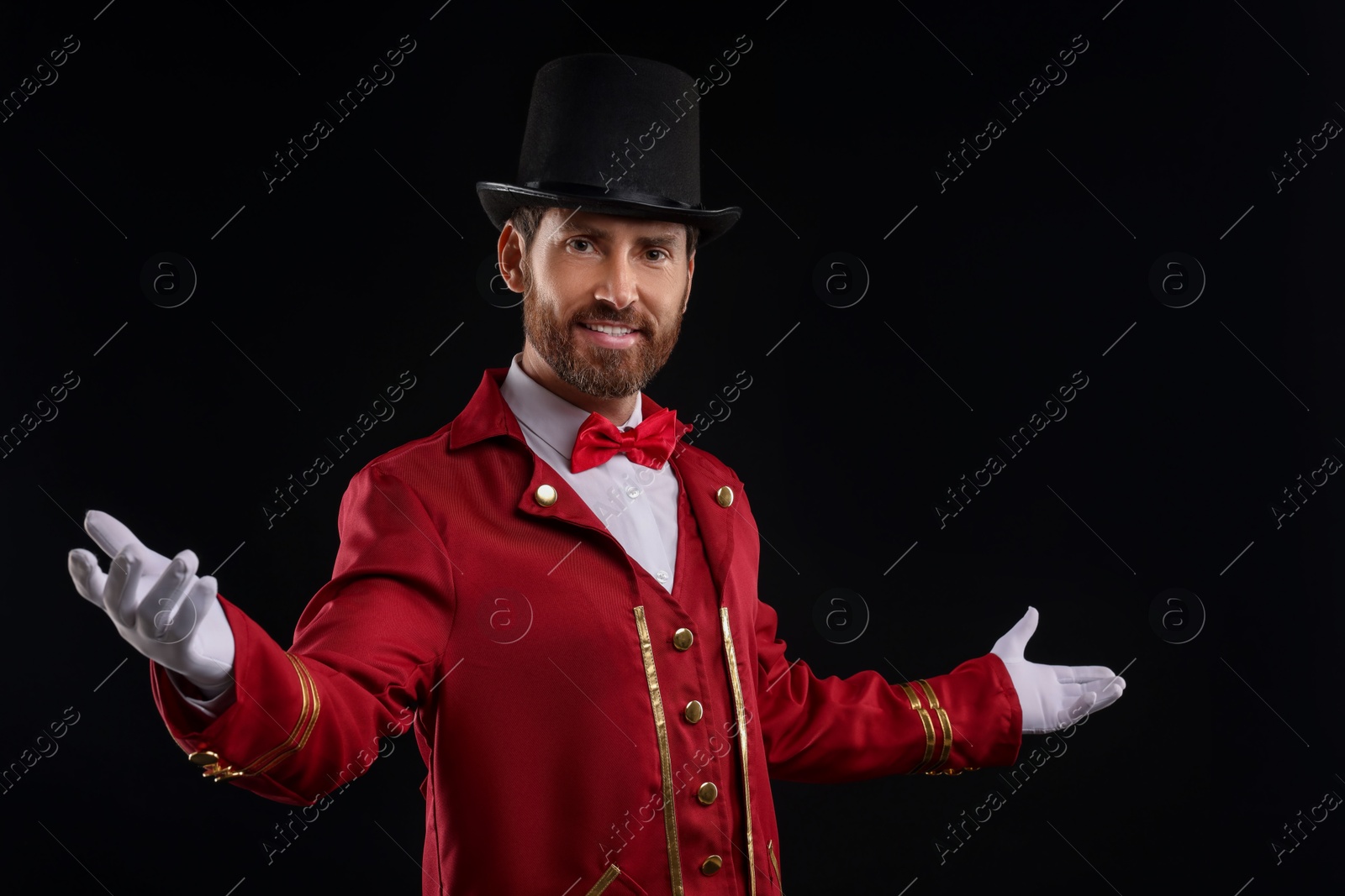 Photo of Portrait of showman in red costume and hat on black background