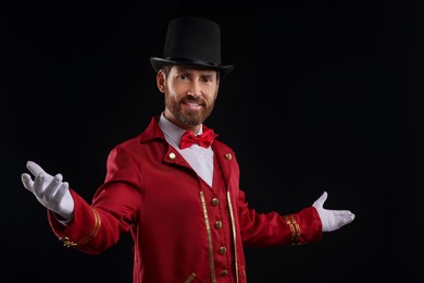 Photo of Portrait of showman in red costume and hat on black background