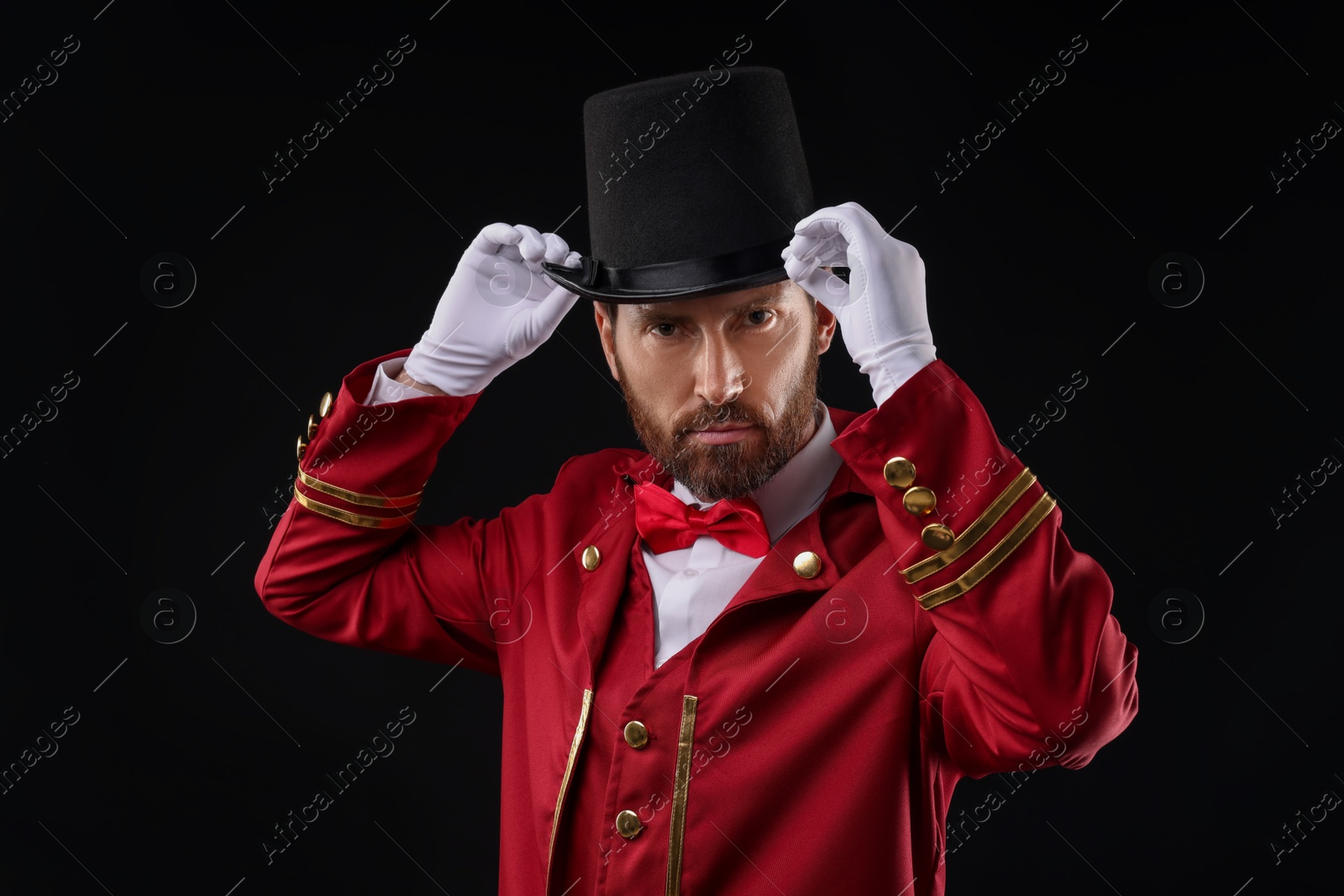 Photo of Portrait of showman in red costume and hat on black background