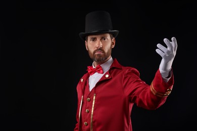 Portrait of showman in red costume and hat on black background